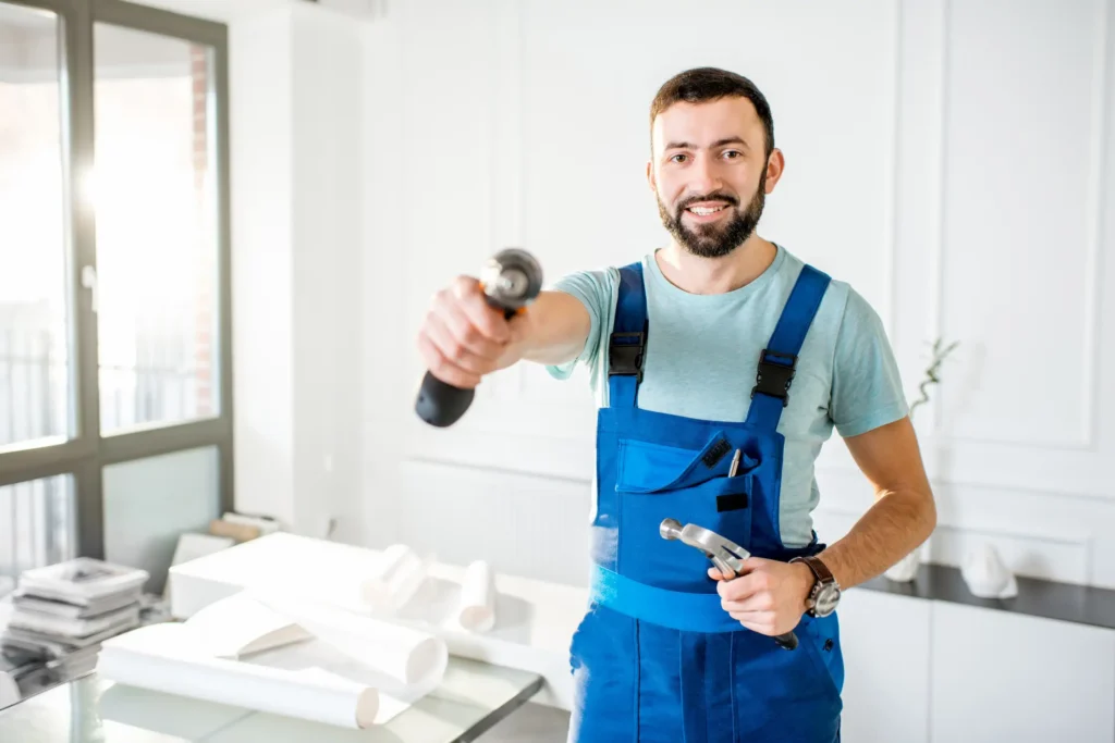 Professional handyman carefully hanging picture frames and artwork on living room wall in Dubai home using level and proper mounting hardware